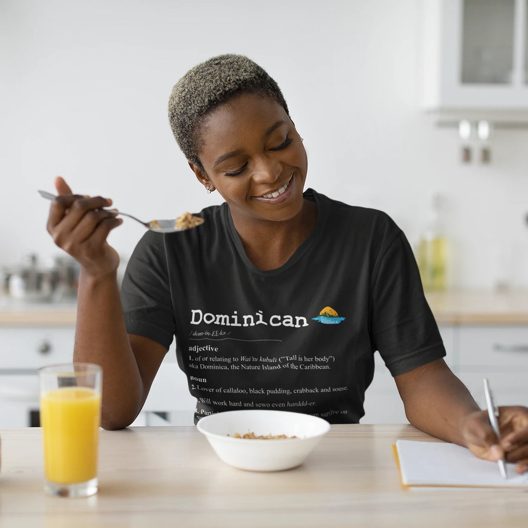 Dark skinned woman wearing a "Dominican Defined" t-shirt in black color, with white text, by Embrace Dominica