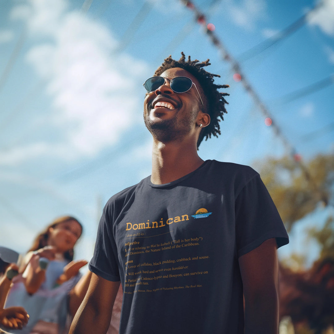 Dark skinned man wearing a "Dominican Defined" t-shirt in navy color, with gold text, by Embrace Dominica