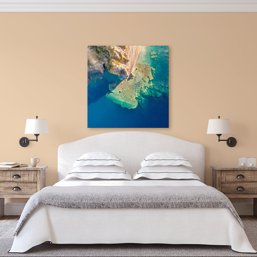 A canvas print of "Coral Reefs at Scotts Head" by Yuri A Jones on a peanut colored wall, above a king sized bed.
