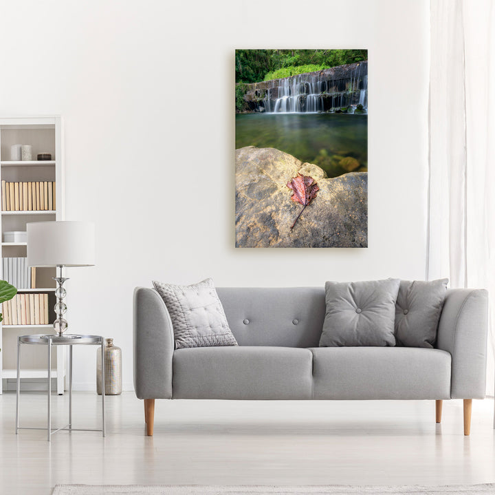 A canvas print of "On the Edge" by Yuri A Jones on a white wall, hung above a gray couch.