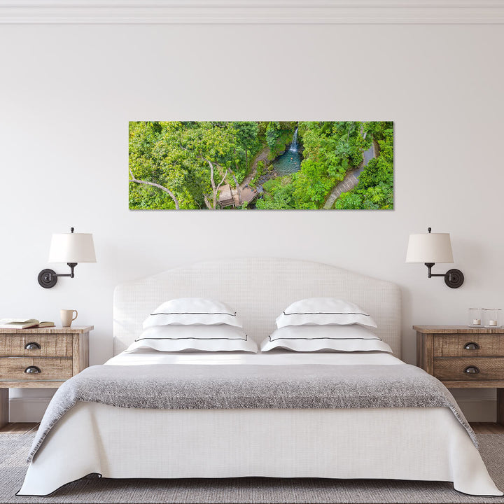 A canvas print of "Emerald Pool Swimmers" by Yuri A Jones on a white wall, above a queen sized bed.