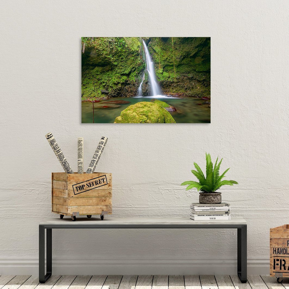 A canvas print of "Majestic Falls" by Yuri A Jones on a white stucco wall, hung above a bench with a white top.