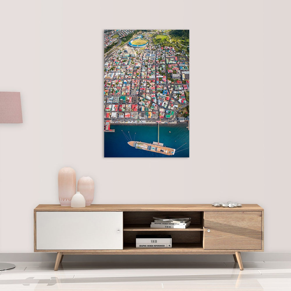 A canvas print of "Mein Schiff I" by Yuri A Jones on a light colored wall, hung above a 70s style wooden desk.