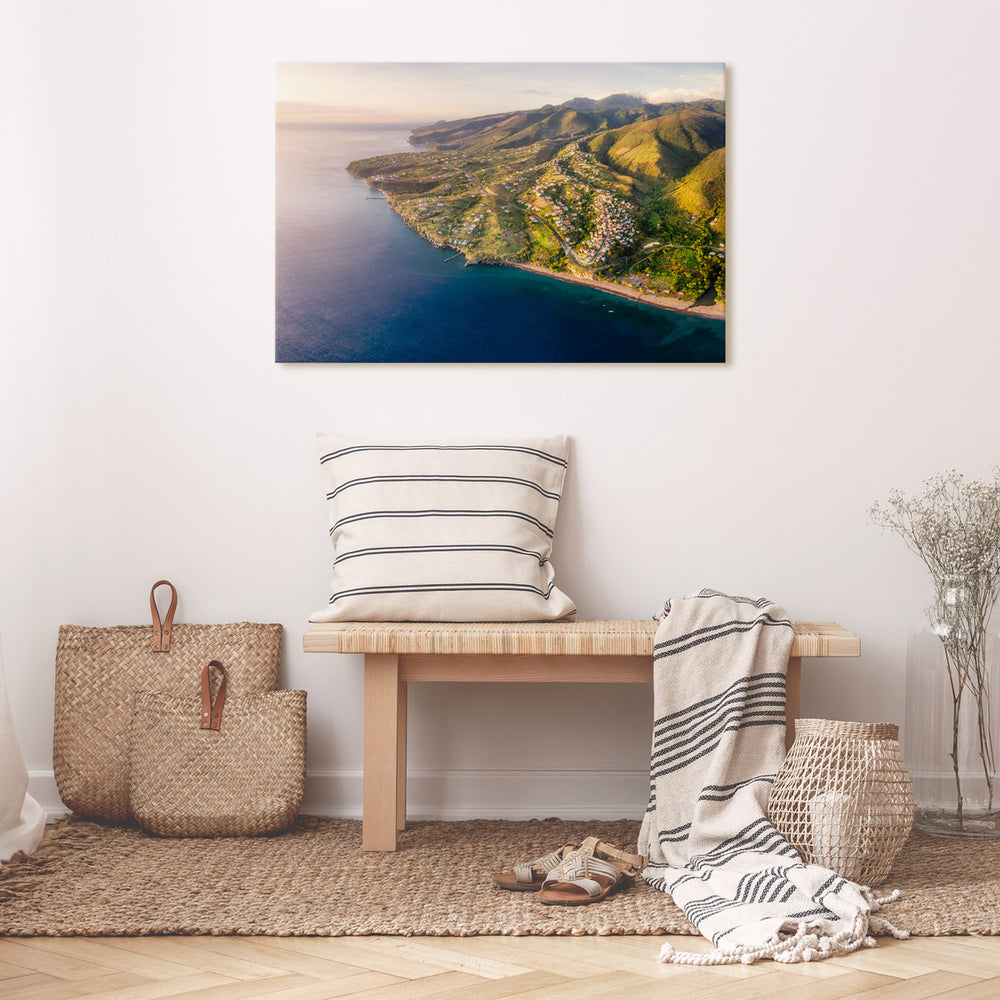 Canvas print of "Bawi Sunset" by Yuri A Jones, hung on a cream colored wall, above a bench.