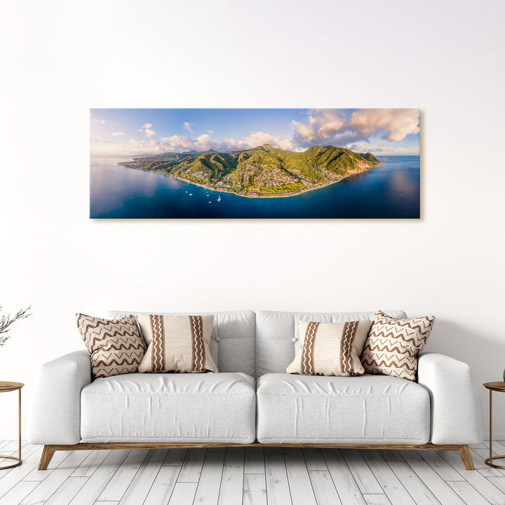 A canvas print of "Dominica SW From Above" by Yuri A Jones hung on a white wall above a light gray sofa.