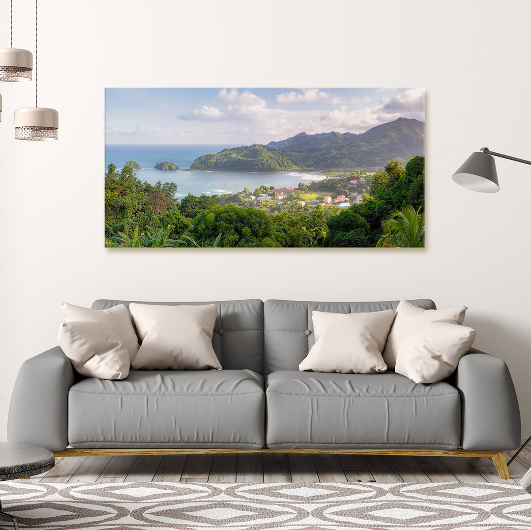 A canvas print of "Islet View" by Yuri A Jones on a white wall, hung above a gray sofa with five different light-brown pillows.