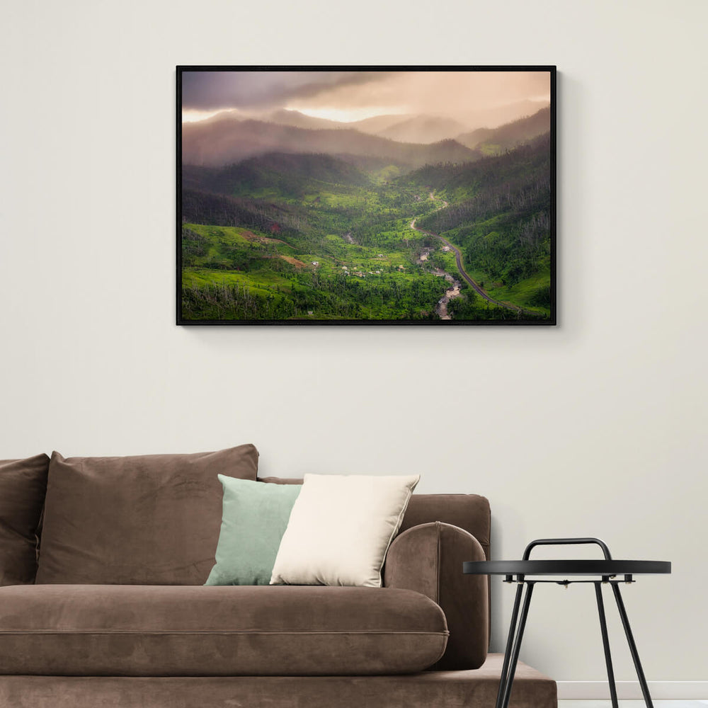 A framed canvas print of "Coming Rain" by Yuri A Jones on a white wall above a brown couch.