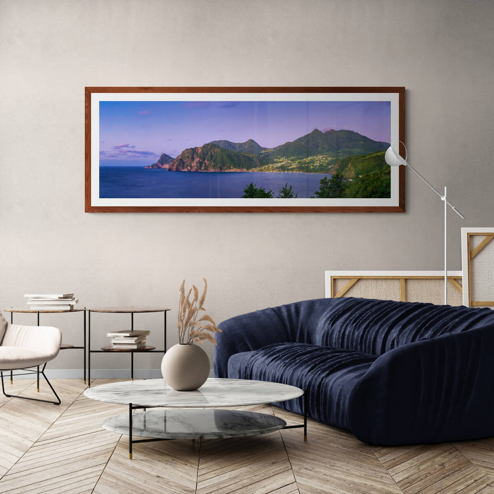 A framed art print of"Grand Bay at Blue Hour I" by Yuri A Jones on a light colored wall, hung over a blue couch.