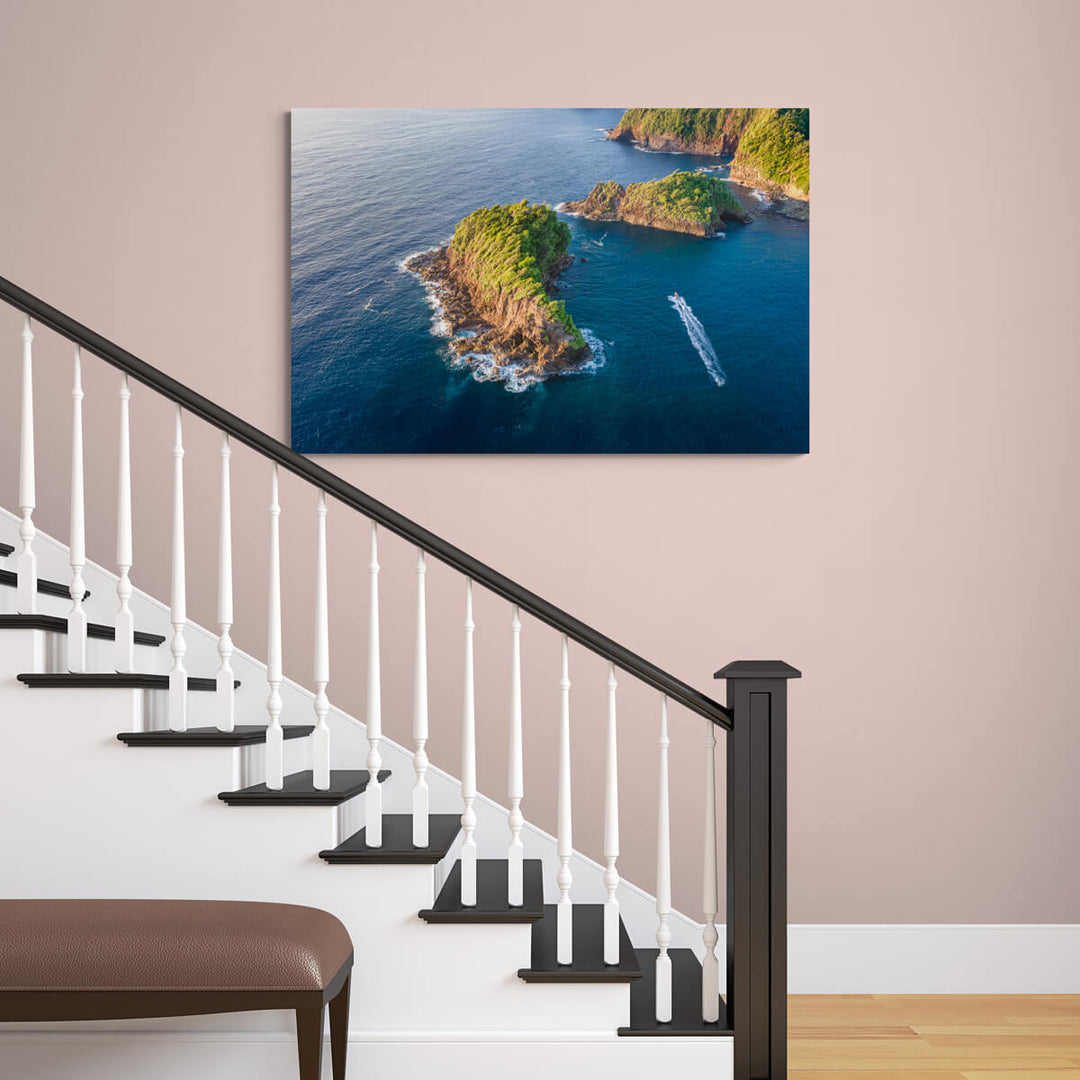 A canvas print of "Islet Sunrise I" by Yuri A Jones on a faded pink wall, hung over a staircase with black floor panels and white banisters.