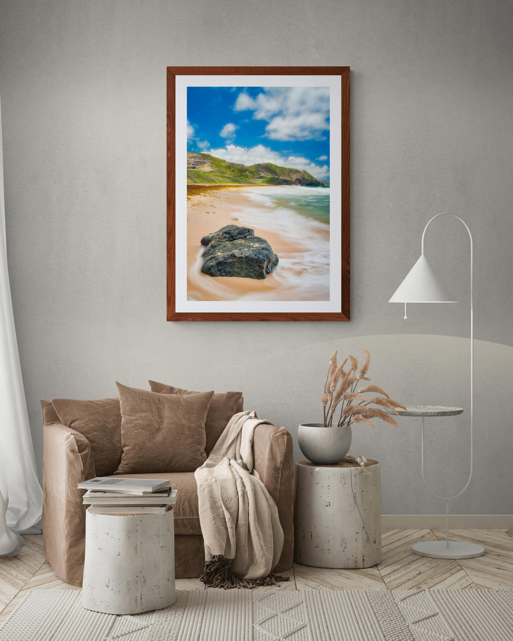 A framed art print of "North Friar's Bay I" by Yuri A Jones on a gray wall, hung above a brown armchair.