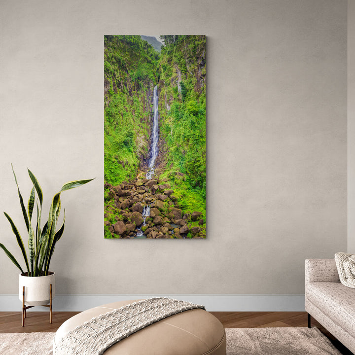 A canvas print of "Papa Falls" by Yuri A Jones on a eggshell colored wall, above a plant.